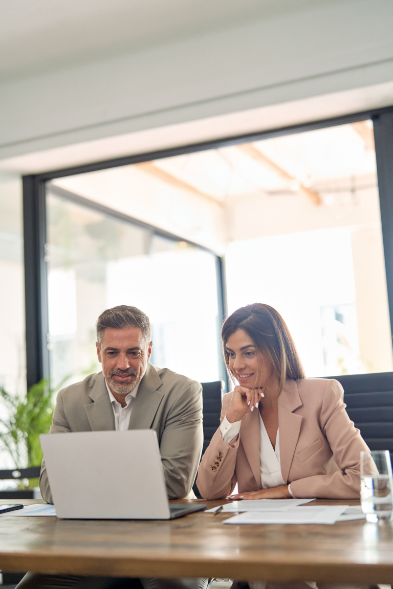 two-happy-professional-business-executives-working-in-office-looking-at-laptop-1-1